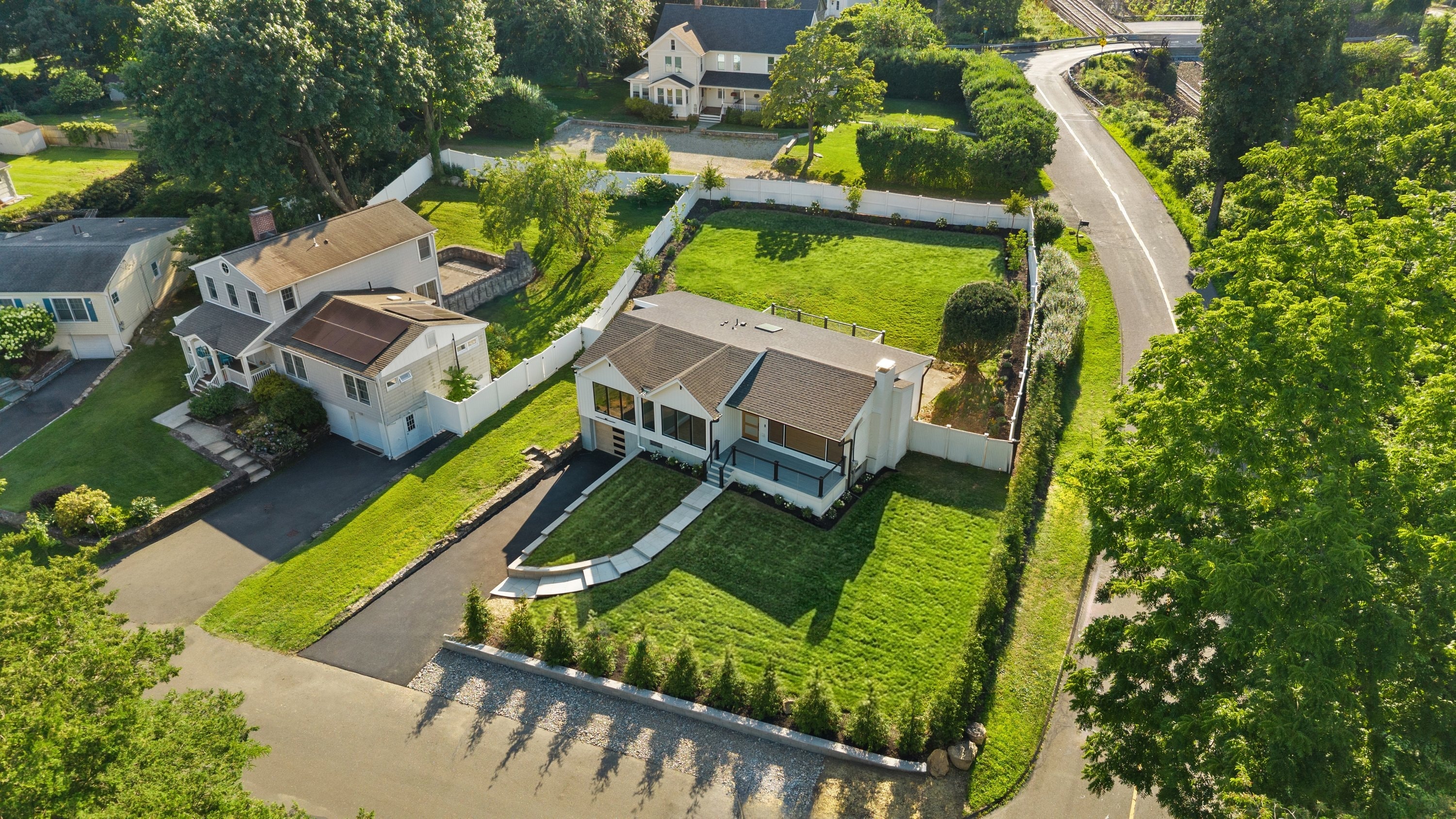 Aerial view of renovated modern home with manicured landscaping and circular driveway