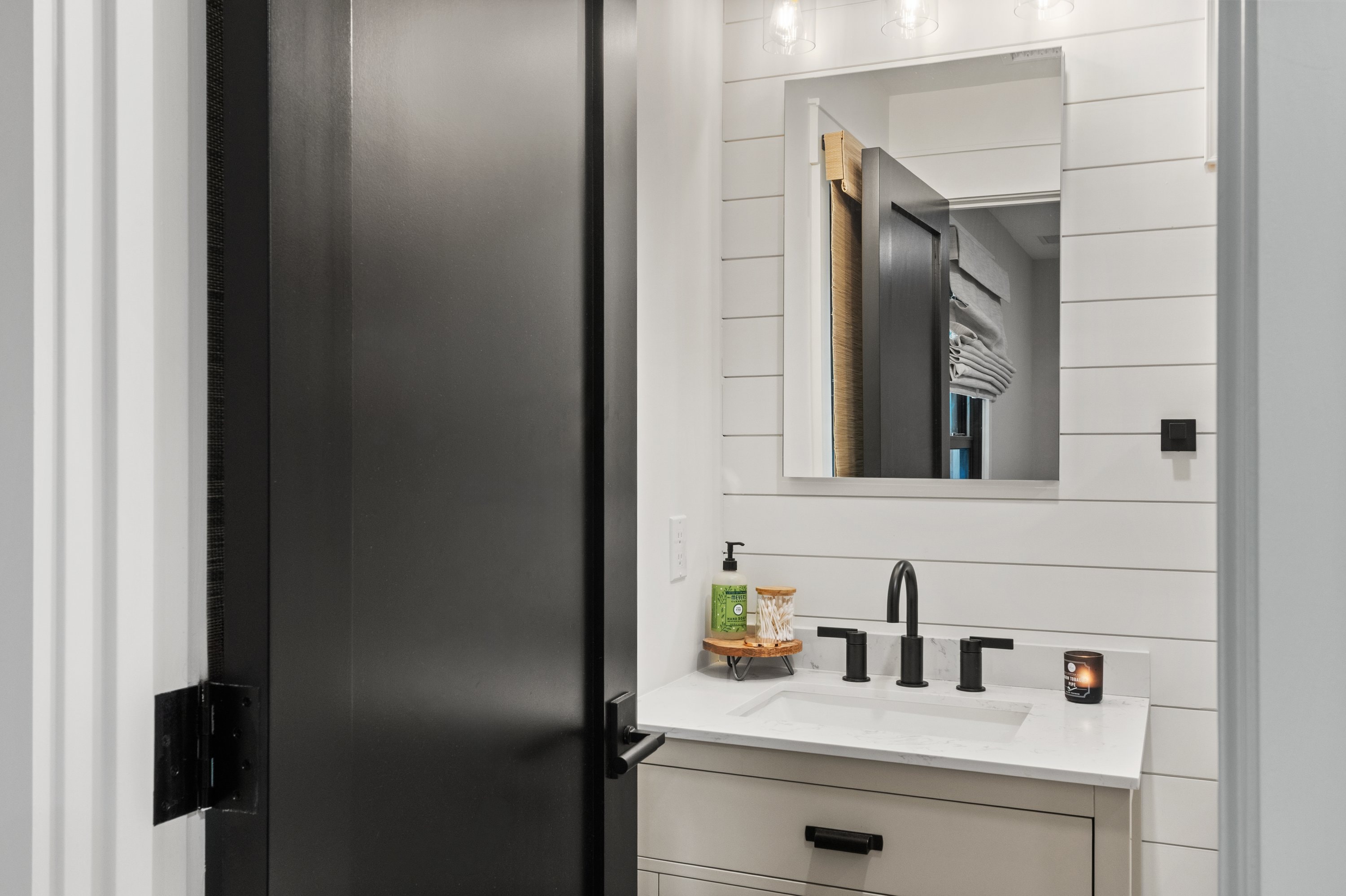 Guest bathroom with black barn door, shiplap walls, and marble-top vanity