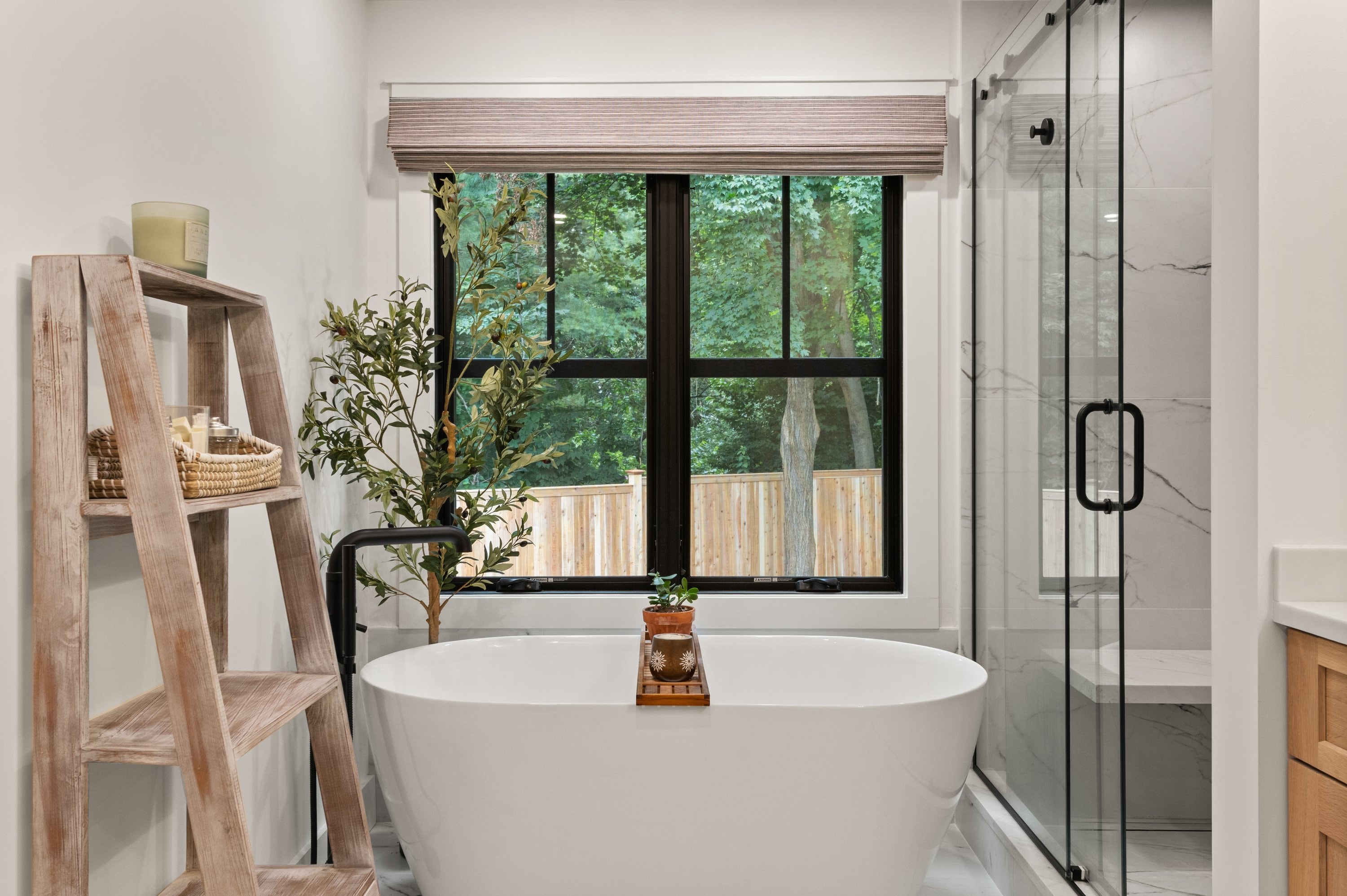 Primary bathroom freestanding soaking tub with garden window and marble shower enclosure