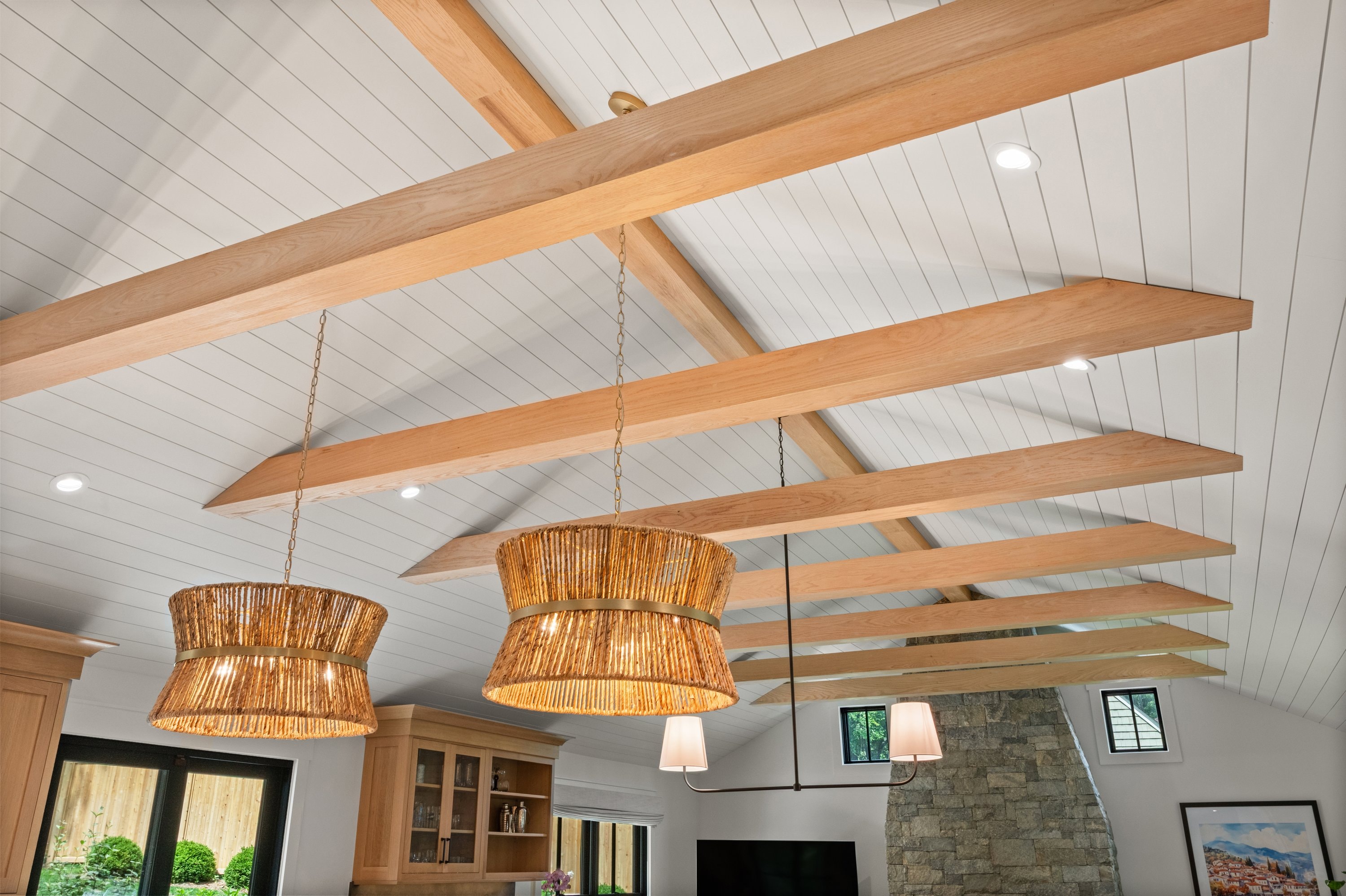 Vaulted shiplap ceiling with custom oak beams and woven rattan pendant lights