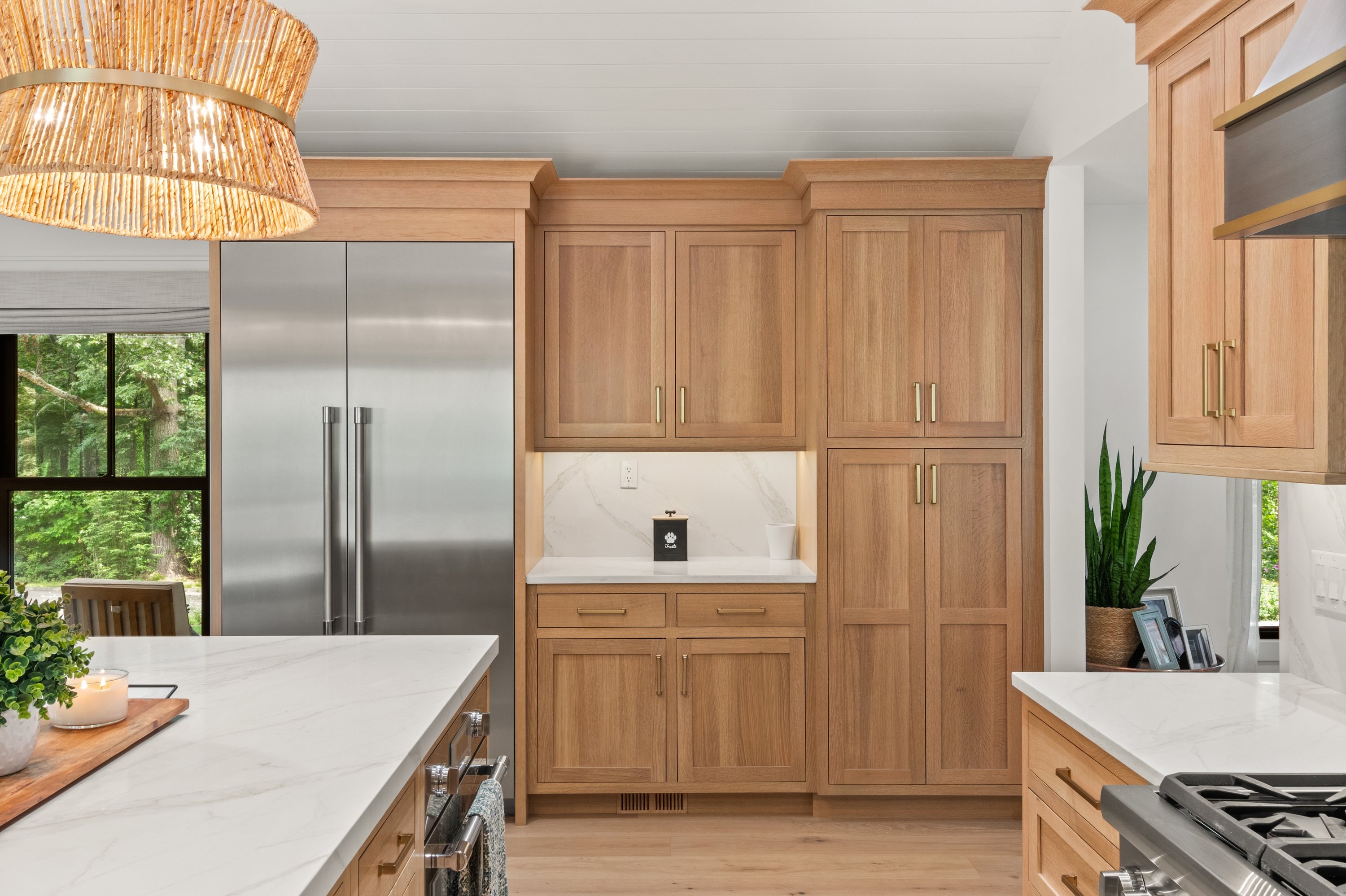 Custom oak kitchen cabinetry with brass hardware, marble countertops, and Sub-Zero refrigerator