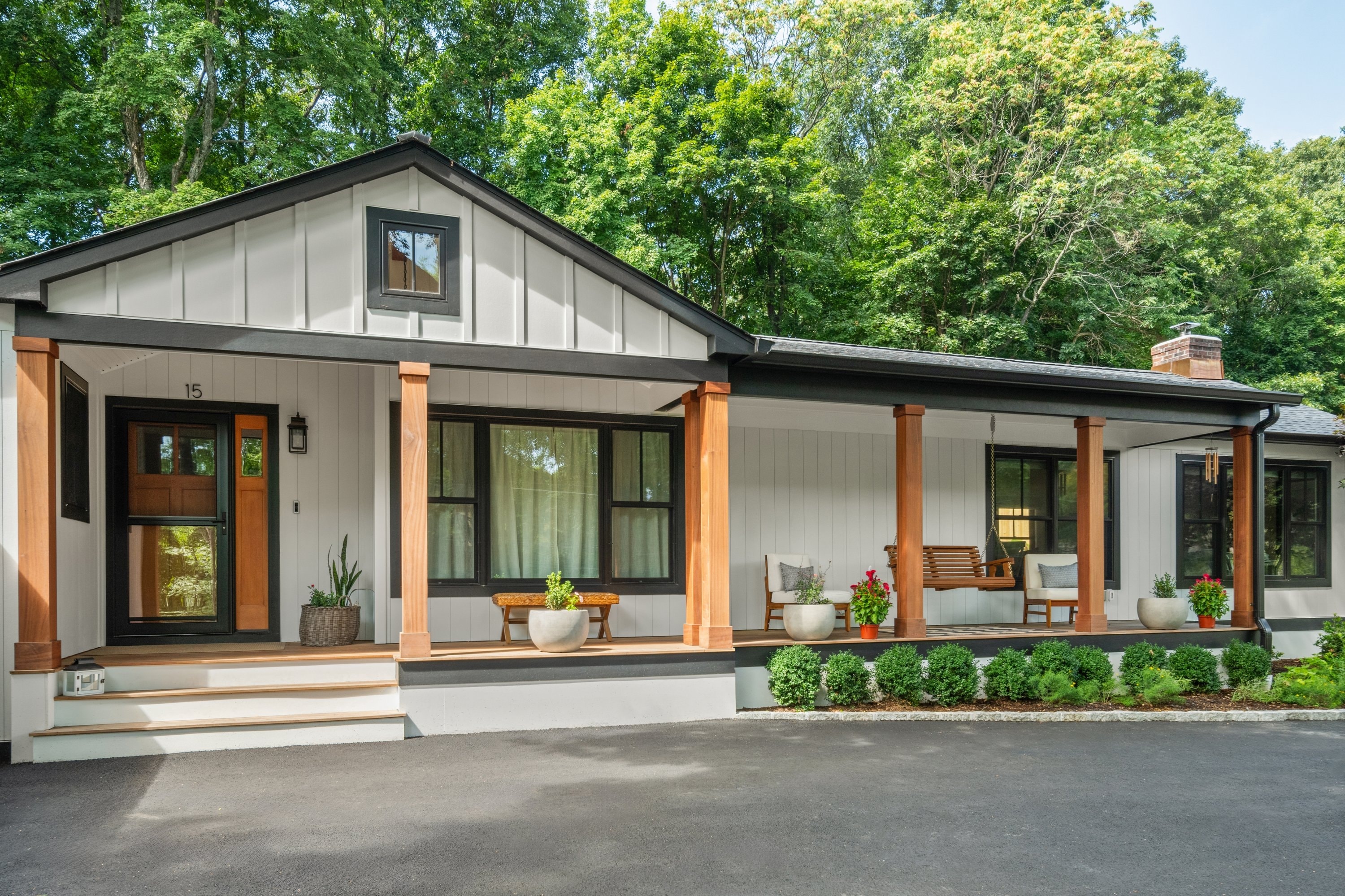 Modern farmhouse with covered porch, cedar columns, and swing — angled view