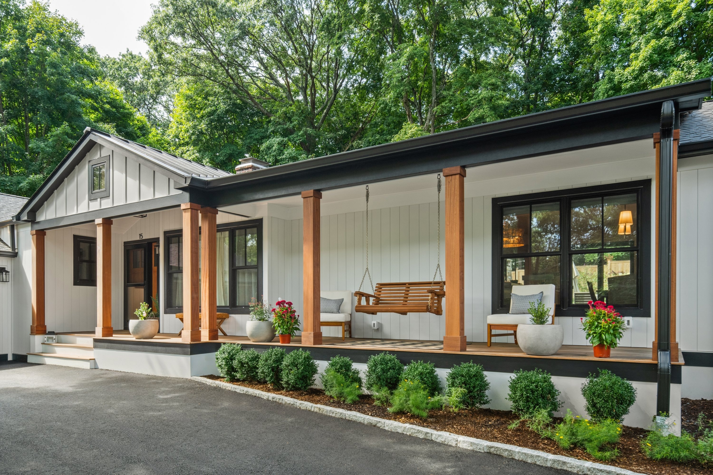 Modern farmhouse renovation with covered front porch, cedar columns, and porch swing