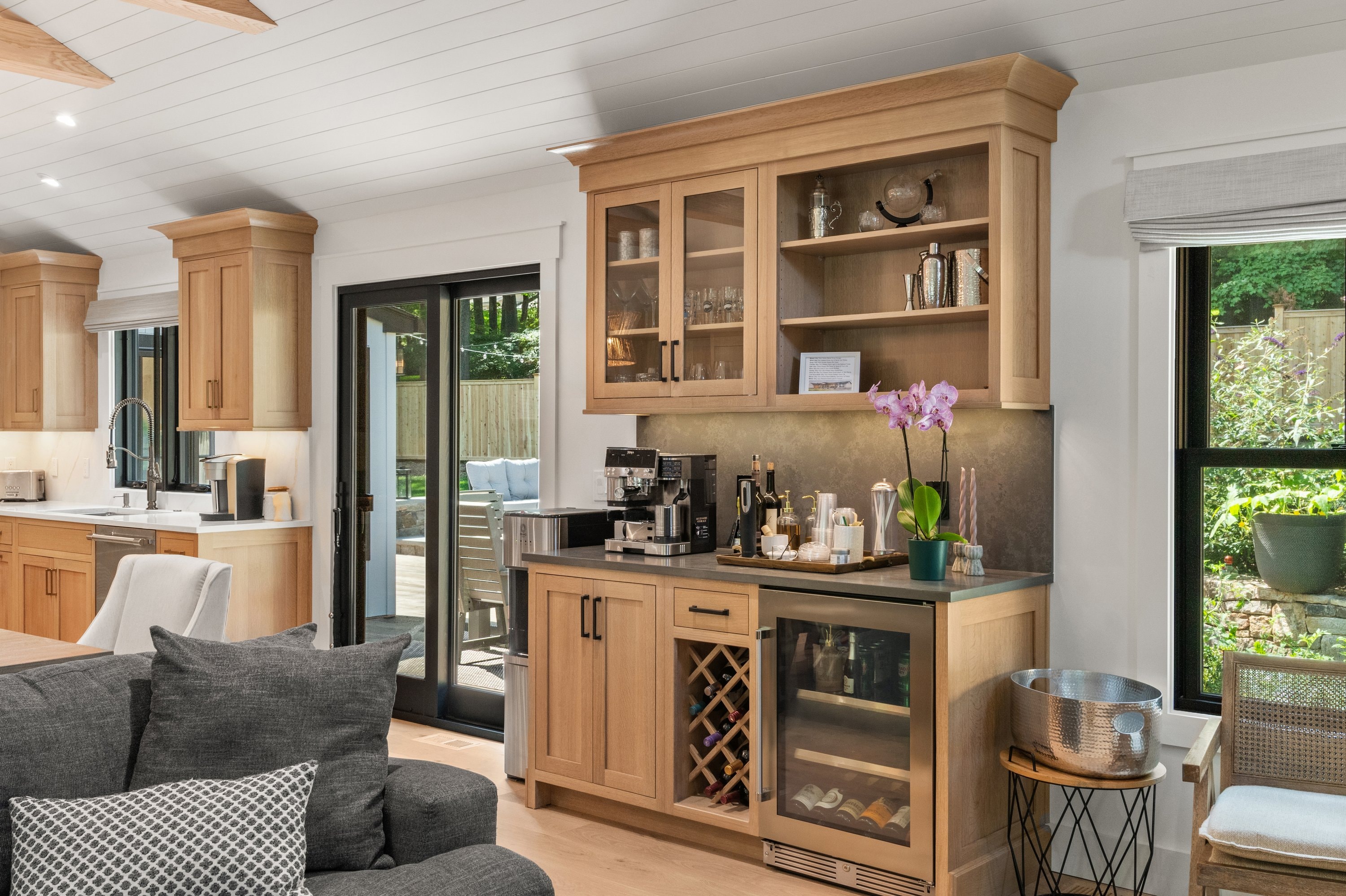 Custom wet bar with oak cabinetry, glass-front uppers, wine fridge, and coffee station